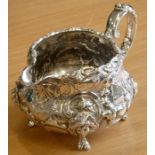 A large 19th century hallmarked silver milk jug, decorated in high relief repoussé style with 'C'