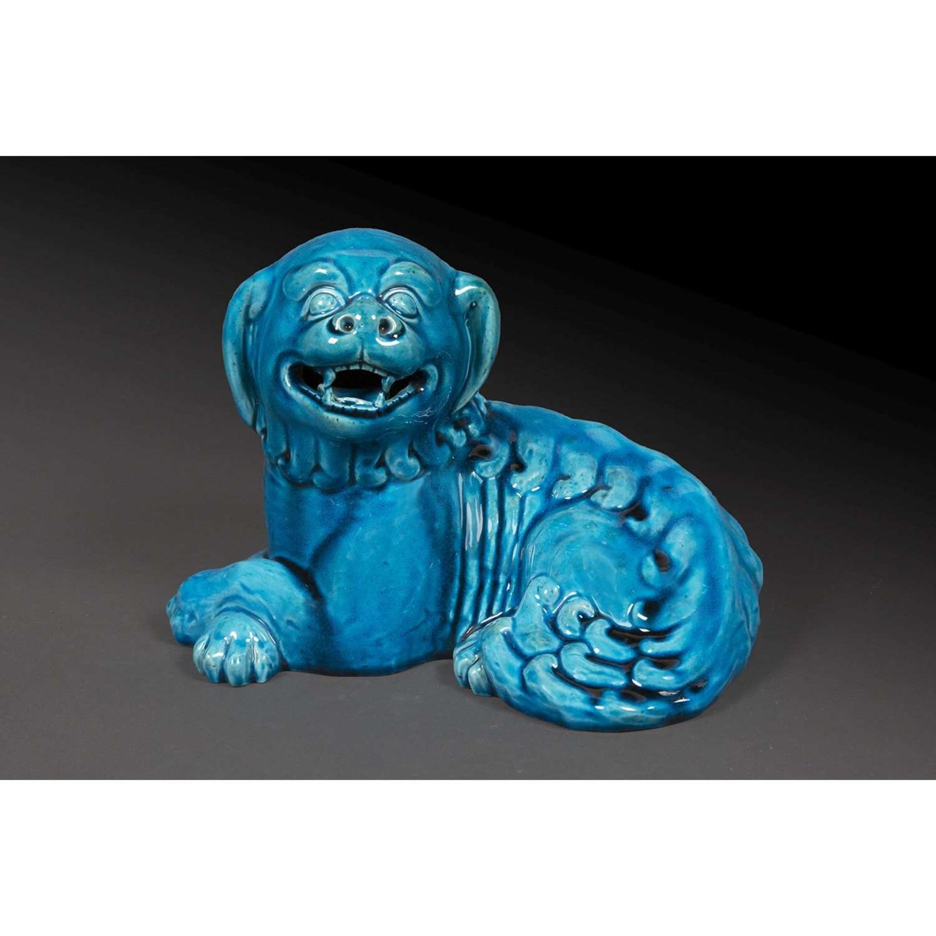 SUJET ANIMALIER en porcelaine émaillée turquoise, représentant un chien couché, la tête dressée,