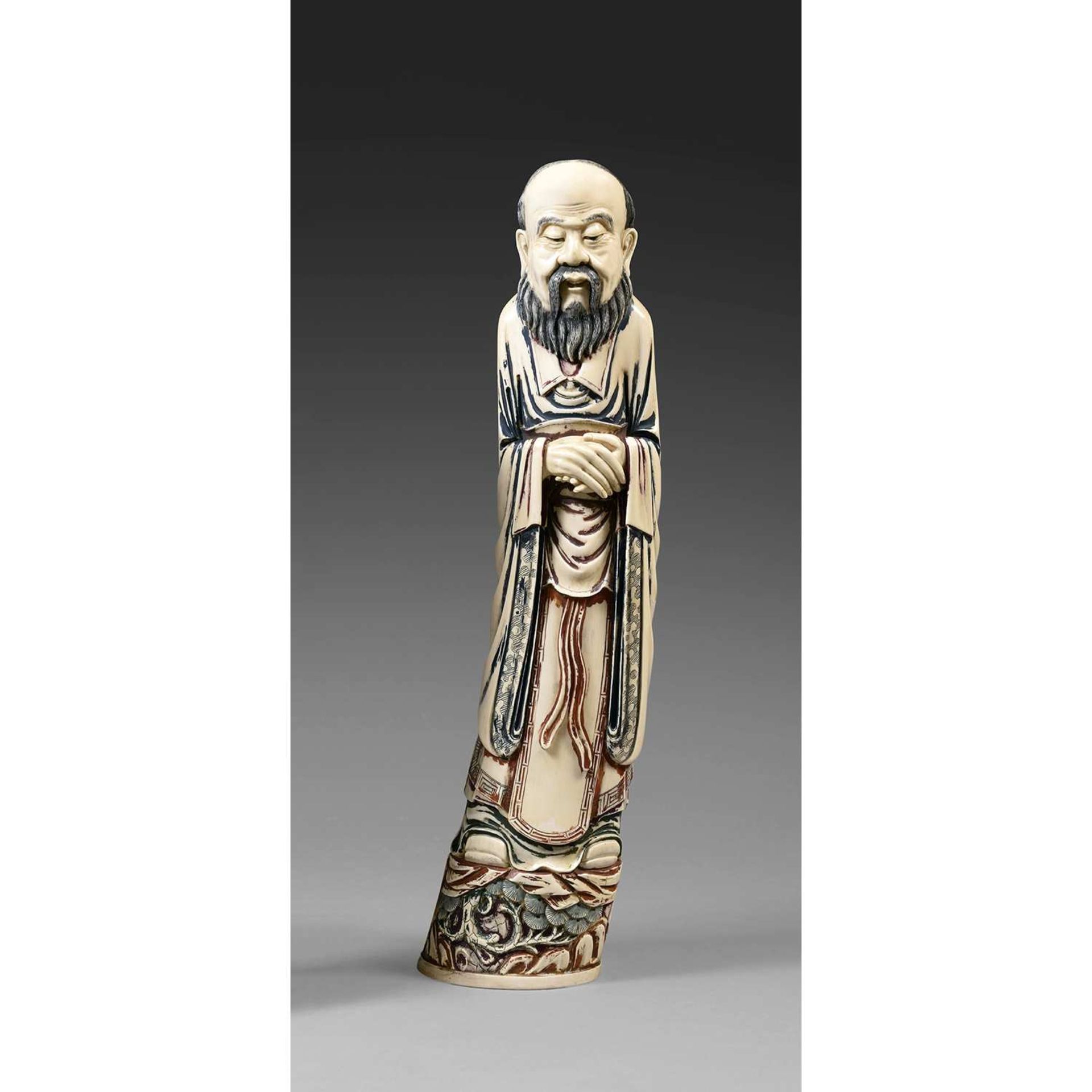 ~ GRANDE STATUETTE DE SAGE en ivoire rehaussé de polychromie, représenté debout sur un rocher, les