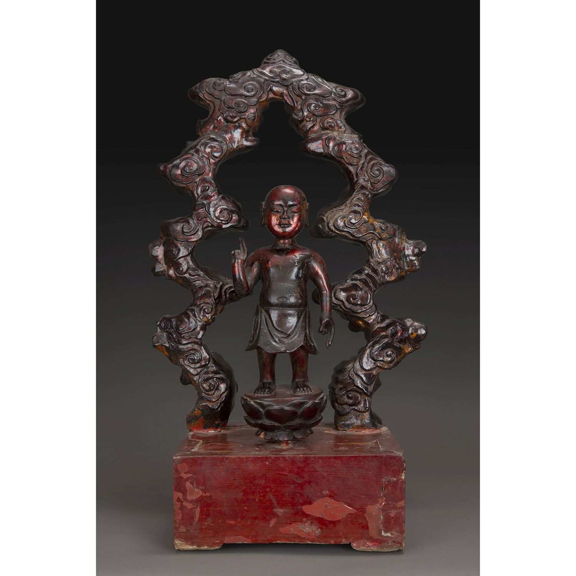 STATUETTE DU BOUDDHA ENFANT en bois laqué rouge et doré, représenté debout sur le lotus, la main