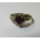 A marked DIA 375 gold ruby and diamond accent heart ring. Set with a central heart shaped ruby on