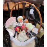 A basket of two porcelain dolls, three smaller plastic dolls in European costume and one in