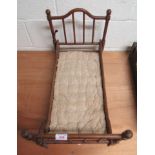 An early wooden doll's bed with quilted mattress