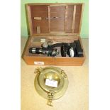 A boxed microscope with glass slides together with a brass ashtray fashioned like a ships porthole.