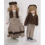 Two Porcelain dolls on stands of a boy and a girl in matching Victorian outfits