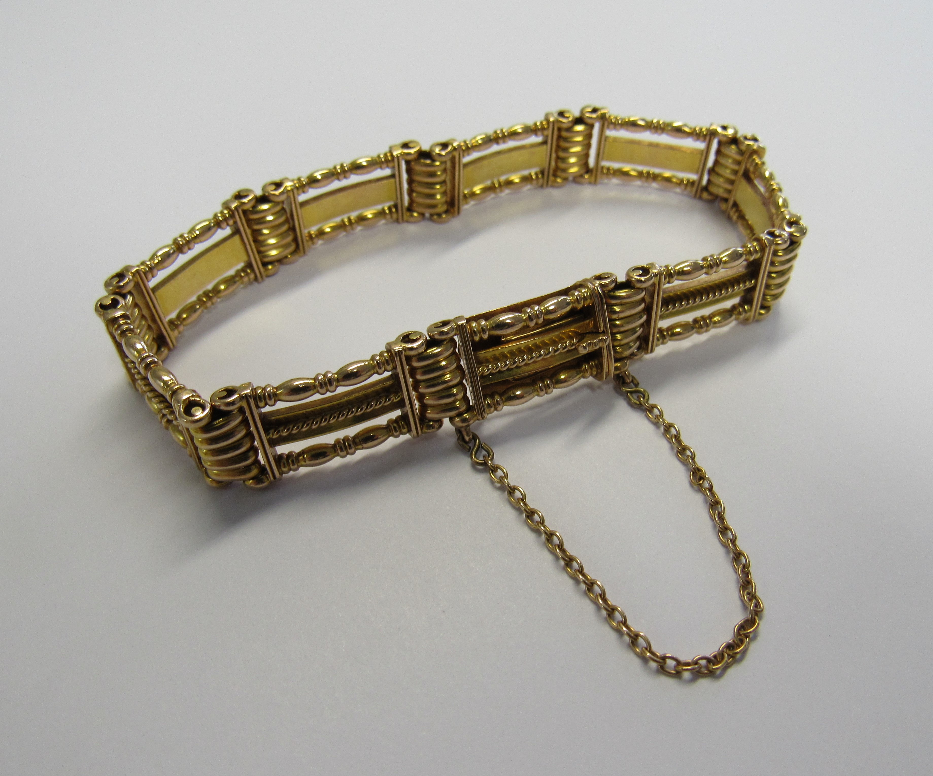 A 15ct gold slide clasp ornate, finely made three bar gate bracelet with attached safety chain. Back