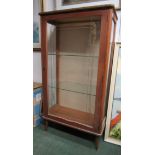 A small glass display cabinet with two glass shelves and gold pattern scroll decoration on opening