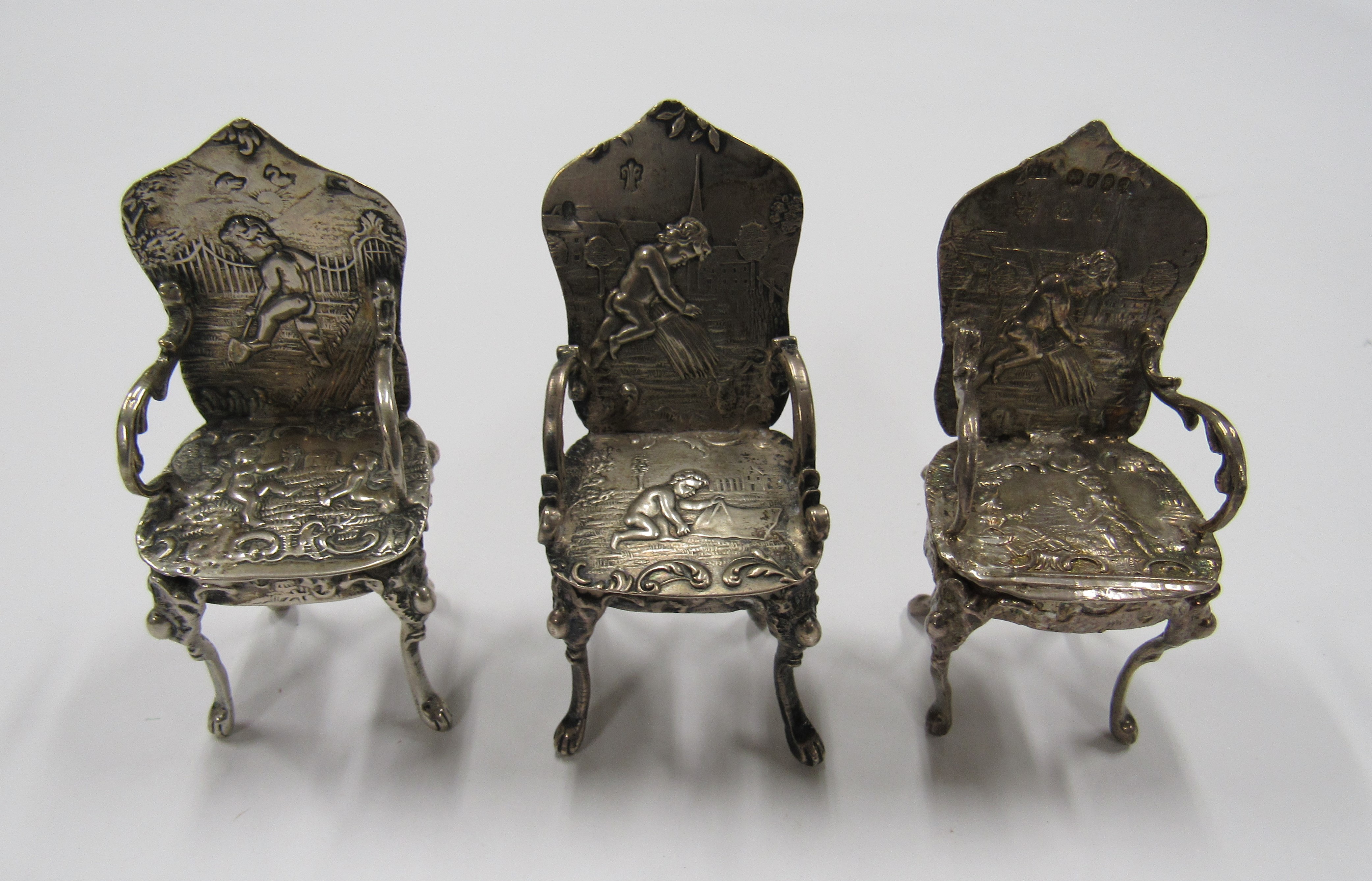 Three silver miniature dolls house high backed chairs, in similar repousse style of embossed