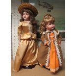 Two porcelain dolls on stands, one jointed. Unboxed and dressed in turn of the century attire.
