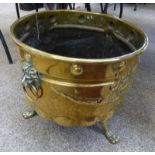 LATE 19TH CENTURY EMBOSSED BRASS COAL/LOG BIN ON SHAPED LION PAW SUPPORTS WITH LION HEAD HANDLES