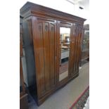 ART NOUVEAU WALNUT MIRROR DOOR WARDROBE WITH STYLISED PANEL DOORS FLANKING A MIRROR DOOR ON BRACKET