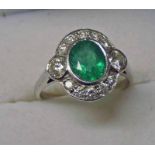 AN 18CT WHITE GOLD EMERALD & DIAMOND CLUSTER RING & THE OVAL EMERALD SET WITHIN A SURROUND OF 12