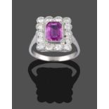 A Pink Sapphire and Diamond Cluster Ring, the emerald-cut pink sapphire within a border of round