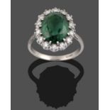 A Green Tourmaline and Diamond Cluster Ring, the oval cut green tourmaline within a border of