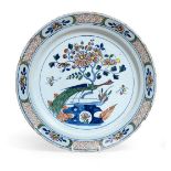 ^ An English Delft Dish, circa 1750, painted in colours with a pheasant perched on rockwork beside a