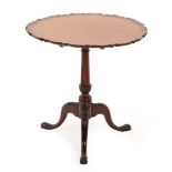 A George III Style Mahogany Pie Crust Tripod Table, the flip-top on a baluster acanthus carved