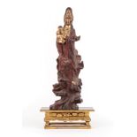 A Parcel Gilt Rootwood Figure of Guanyin, Qing Dynasty, standing wearing flowing robes holding a