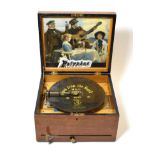 A 9 1/2-inch Polyphon Disc Musical Box, with single comb, titled gilt bedplate, blond oak