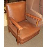 An early 20th century brown leather open armchair