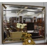 A reproduction bevelled glass sectional mirror with silvered frame, 115cm by 146cm