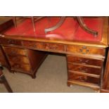 A reproduction mahogany pedestal desk with tooled red leather writing surface