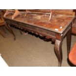 A George III style mahogany serving table with gadrooned border and carved apron, raised on cabriole