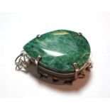 An emerald pendant, the pear cut emerald in a white claw setting to a scroll border, measures 7.