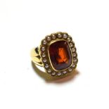 An 18 carat gold hessonite garnet and seed pearl cluster ring, the cushion cut hessonite garnet in a