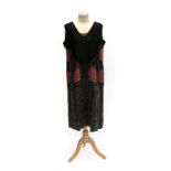 A 1920's Black Silk Flapper Dress, with pink silk appliqué roundels, a skirt of panelled strips