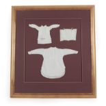 A Framed Display of Three 19th Century School Sewing Samples, including a white cotton corset with