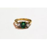 An 18 carat gold emerald and diamond three stone ring, finger size I1/2. Gross weight 3.3 grams.