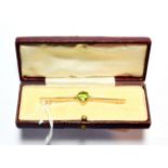 An early twentieth century peridot and seed pearl brooch, an oval cut peridot in a claw setting,