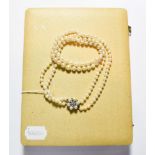 A two row cultured pearl necklace, knotted to a cultured pearl and paste set clasp, length 49.5cm