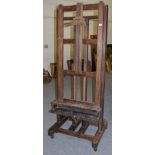 A late 19th/early 20th century large adjustable easel with castors, base measures 81cm wide