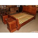 A modern French cherry wood sleigh bed, and a modern pair of bedside cabinets