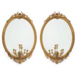 A Pair of Gilt and Gesso Oval Mirrors, circa 1870, the mirror plates within a stiff leaf carved