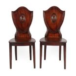 A Pair of George III Mahogany Hall Chairs, circa 1800, the moulded shield back supports above