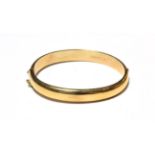 A 9 carat gold hinged bangle, with floral engraved detail to the upper section. Gross weight 13.0