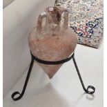 A terracotta wine pot on black painted metal stand