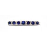 A synthetic sapphire and diamond brooch, seven graduated synthetic sapphires spaced by pairs of