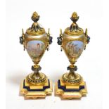 A pair of Continental porcelain and gilt metal mounted urns painted with vignettes and twin mask