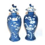 A pair of early 20th century Chinese blue and white prunus and cracked ice baluster vases and covers