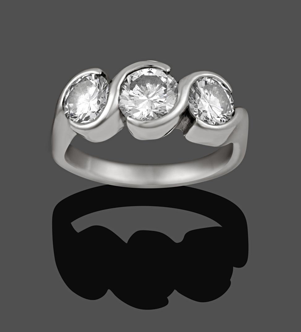 A Diamond Three Stone Ring, the graduated round brilliant cut diamonds in swirl tension settings, to
