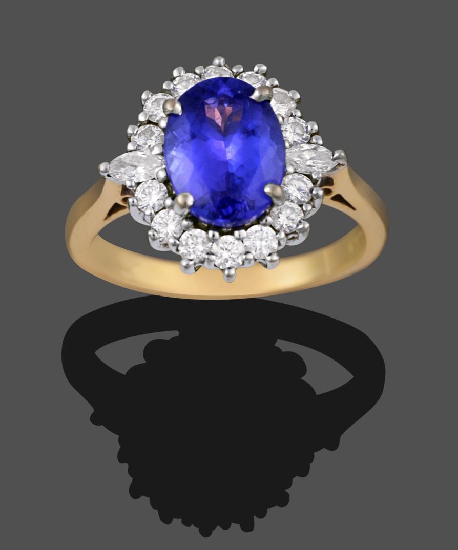 An 18 Carat Gold Tanzanite and Diamond Cluster Ring, the oval cut tanzanite within a border of round