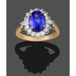 An 18 Carat Gold Tanzanite and Diamond Cluster Ring, the oval cut tanzanite within a border of round