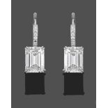 A Pair of Diamond Drop Earrings, an emerald-cut diamond in a white double claw setting suspended