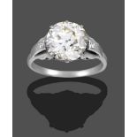 A Diamond Solitaire Ring, the old cut diamond in a white claw setting, to fancy panelled shoulders