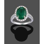 An 18 Carat Gold Emerald and Diamond Cluster Ring, the oval cut emerald in a yellow four claw