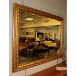 ^ A rectangular gilt framed hall mirror with conforming bevelled plate and leaf and rope carved
