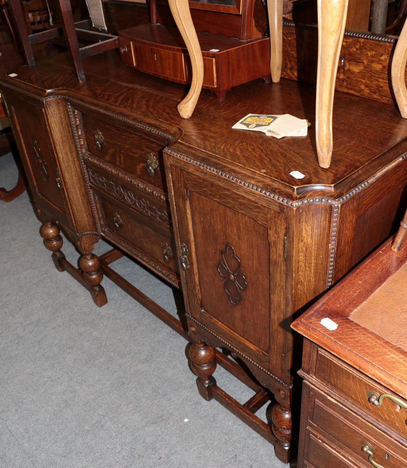 ^ A 1930's carved oak inverted breakfront sideboard, with egg and dart decoration, turned legs and